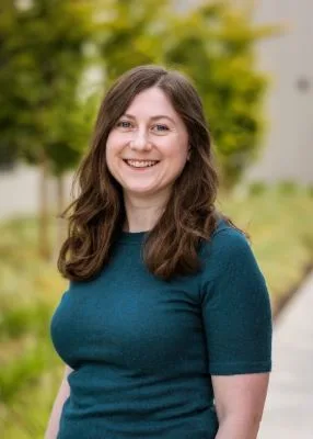 A woman engineer, smiling and wearing a green sweater