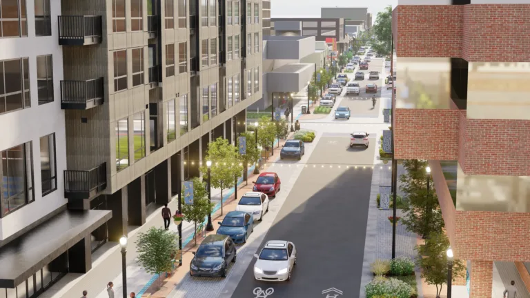 3D rendering of a modern downtown street with mid-rise buildings, trees, lampposts and string lights, angled street parking, a bike symbol on the roadway, and pedestrians on wide sidewalks.