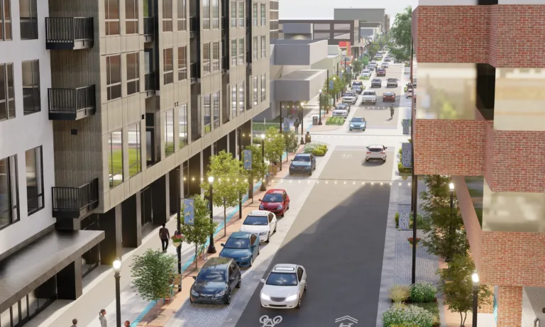 3D rendering of a modern downtown street with mid-rise buildings, trees, lampposts and string lights, angled street parking, a bike symbol on the roadway, and pedestrians on wide sidewalks.