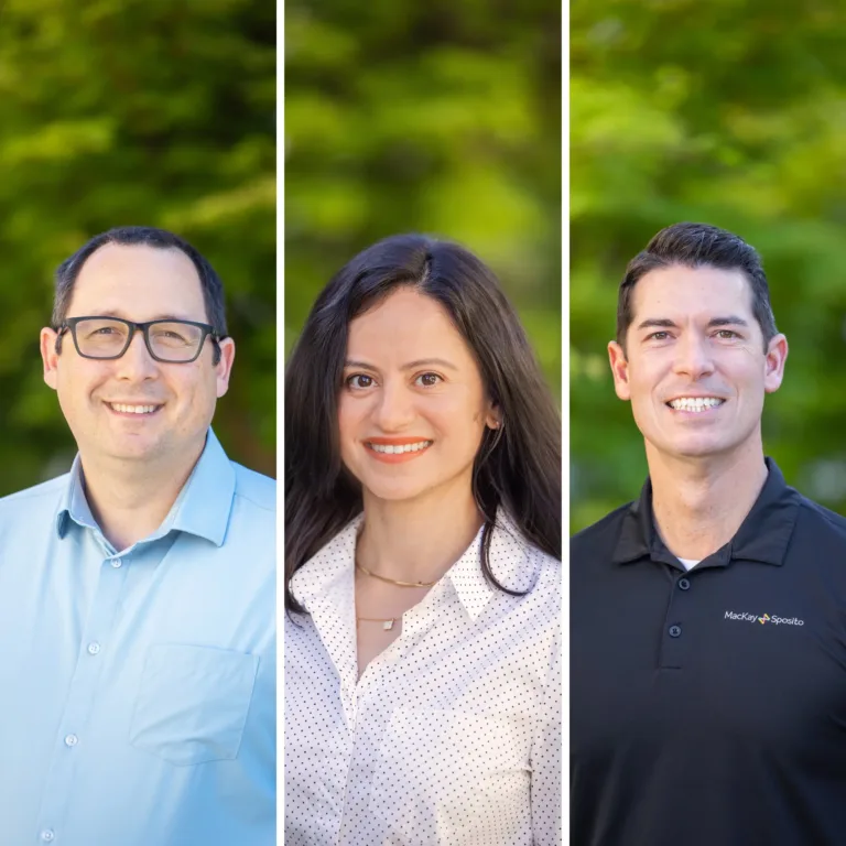 Side-by-side portraits of three smiling professionals outdoors, separated by white bars: left in a light blue button-down and glasses, center in a white polka-dot blouse, and right in a black polo with the MacKay Sposito logo, all against a blurred green background.